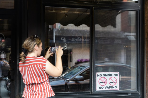 A person takes a photo of a bullet hole in the window of Modern Pastry, a bakery in the North End best known for its cannoli. A 54-year-old Boston man is accused of firing a weapon in the North End Wednesday night. (Chris Van Buskirk/Boston Herald)