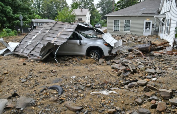A car sits stranded amid debris after historic rains left a swath of damage and destruction in Leominster in September. (Chris Christo/Boston Herald)