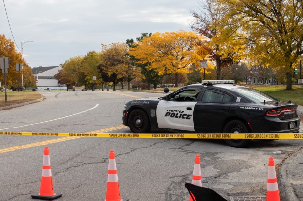 A Lewiston Police Department cruiser sits in front a closed road on Thursday, Oct. 26, 2023, that leads to Sparetime Recreation, one of the sites involved in a mass shooting. (Chris Van Buskirk/MediaNewsGroup/Boston Herald)