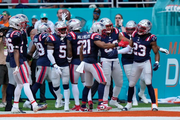 Teammates celebrate an interception by New England Patriots safety Kyle Dugger (23) during the first half of an NFL football game against the Miami Dolphins, Sunday, Oct. 29, 2023, in Miami Gardens, Fla. (AP Photo/Wilfredo Lee)