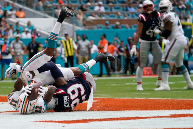 Miami Dolphins wide receiver Cedrick Wilson Jr. (11) scores a touchdown under pressure from New England Patriots cornerback J.C. Jackson (29) during the first half of an NFL football game, Sunday, Oct. 29, 2023, in Miami Gardens, Fla. (AP Photo/Lynne Sladky)