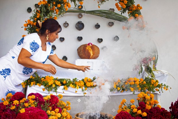 Ana Martínez prepares a Day of the Dead altar at her home's terrace in Santa Maria Atzompa, Mexico, Tuesday, Oct. 31, 2023. Martínez and others in southern Mexico's Oaxaca state wait with anticipation for Day of the Dead celebrations every Nov. 1, when families place homemade altars to honor their dearly departed and spend the night at the cemetery, lighting candles in the hope of illuminating their paths. (AP Photo/Maria Alferez)