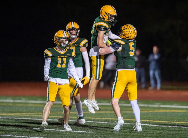 King Philip's Brandon Nicastro is lifted by teammate Daniel Silveria (5) after he intercepted a pass and scored a touchdown during a 23-14 win over Milford. (Amanda Sabga/Boston Herald)