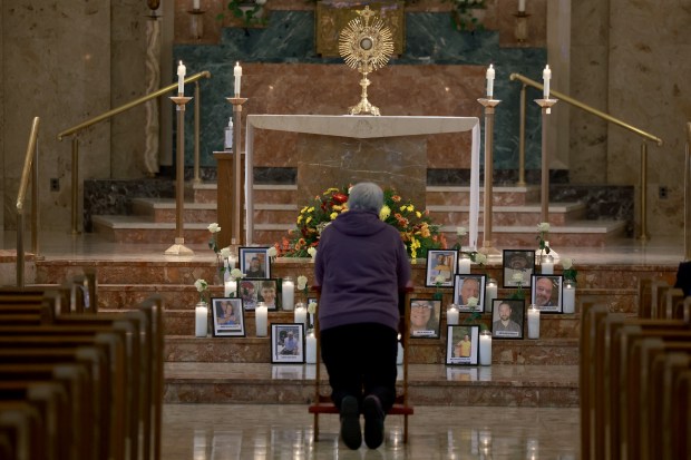 A mourner prays in front of pictures of victims set up during a memorial at the Holy Family Church Sunday, in Lewiston, Maine. (Photo by Joe Raedle/Getty Images)
