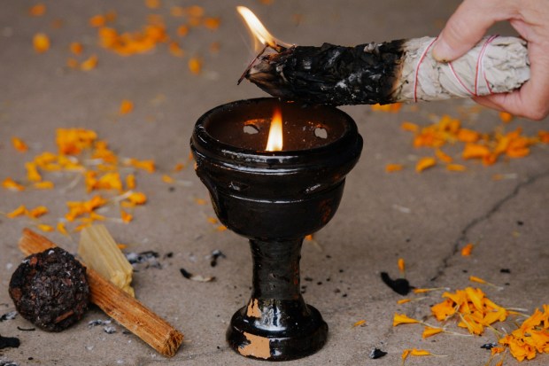 A mixture of palo santo, sage and other traditional Mexican herbs are added to a burner to purify and bless all who will enter Maruca Salazar's home on Dia de los Muertos. (Photo by Amanda Lopez/Special to The Denver Post)